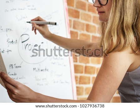 Caucasian woman writing project plan on white board