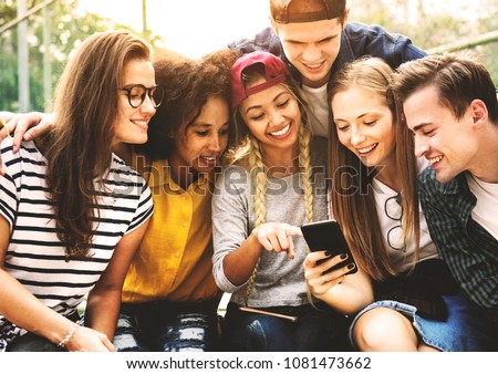 Friends in the park looking using smartphones millennial and youth culture concept
