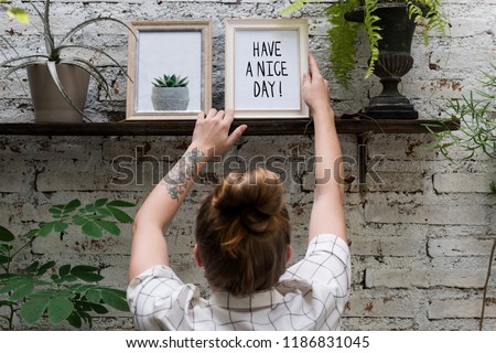 Woman adjusting Have a nice day photo frame on shelf