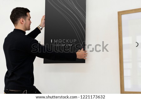 Curator hanging an art piece mockup on the wall in a gallery