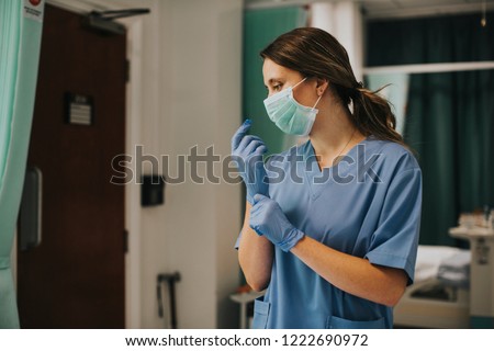 Female nurse with a mask putting on gloves