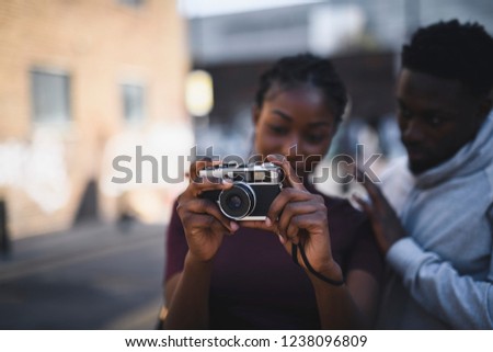 Man teaching his girlfriend how to use a vintage film camera