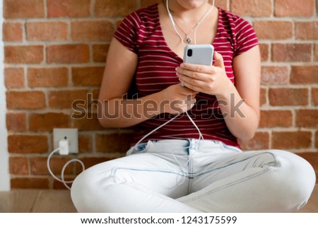 Teen girl using her phone while charging the battery