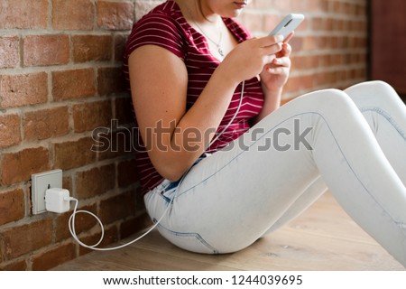 Teen girl using her phone while charging the battery