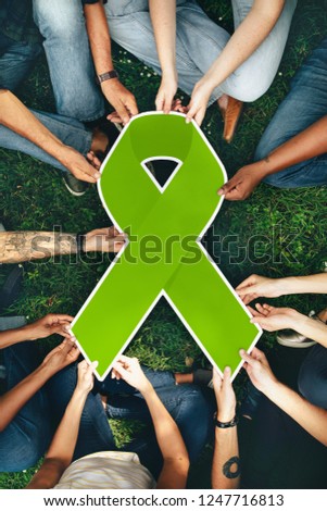 Group of people holding a green colored ribbon