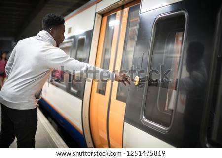 Man pushing a button to open the train doors