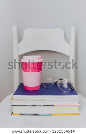Pink travel mug on a stack of textbooks