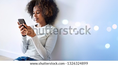 Black woman texting on the floor while charging her phone