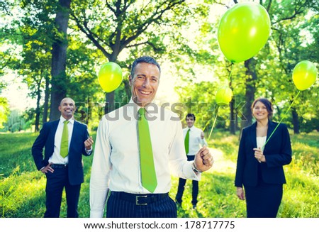 Group of Business People Holding Green Balloons in Forest