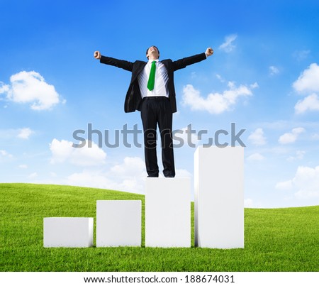 Business Man Standing on a Bar Graph with Arms Raised