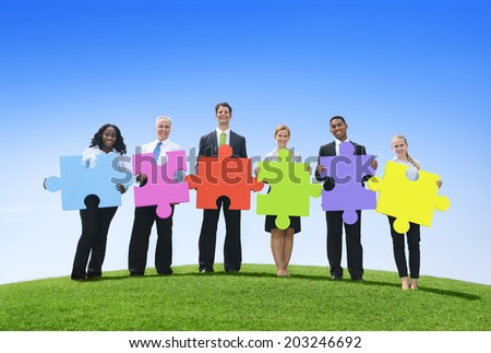 Group of business people holding puzzle pieces.