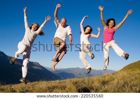 Group of young people jumping in the field.