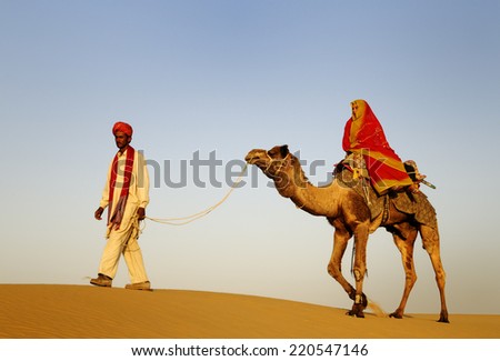 Indigenous Indian man and woman traveling through the desert riding camel.