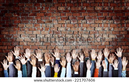 Group of Diverse Hands Raised on Brick Wall