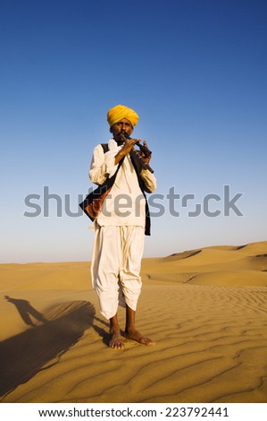 Indigenous Indian man playing wind pipe in a desert.