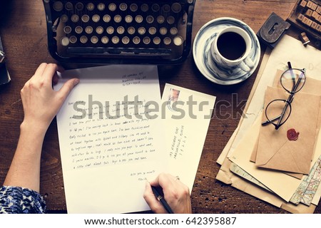 Hands writing the letter on wooden table in aerial view
