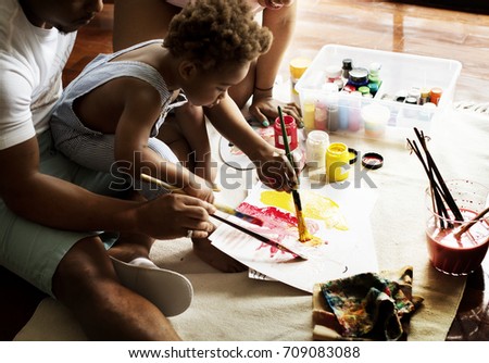 African descent dad teaching his child how to paint