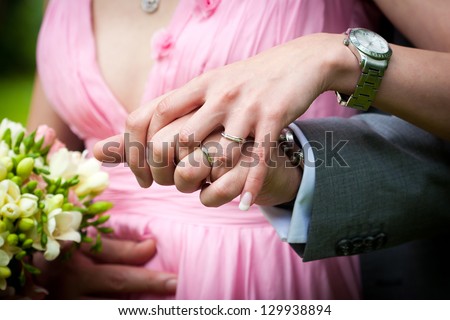 Young married couple holding hands with wedding bouquet