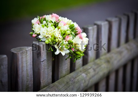 Wedding bouquet with roses and freesia on rustic country fence
