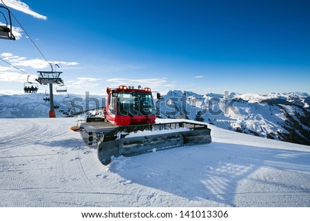 Snow-grooming machine on snow hill ready for skiing slope preparations in Austrian Alps.