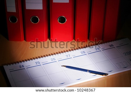 Date book on desk with red files on background
