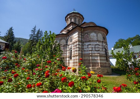 Cozia, Romania - Septemper 2, 2012: Cozia monastery church with red flowers on a sunny summer day, Romania