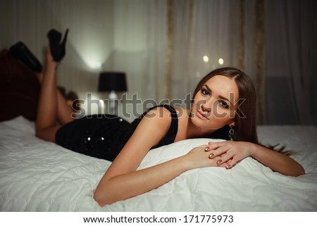 Luxury girl in evening dress, lying on a bed