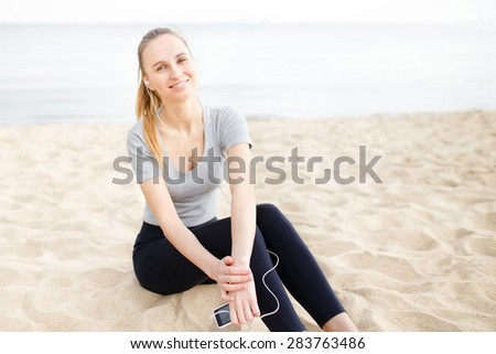 Sports girl on the beach wearing sunglasses listening music