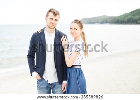 European couple relaxing on the sea beach hugging each other and talking