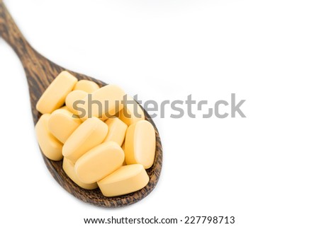 medicine tablets on a wooden spoon isolate on white background