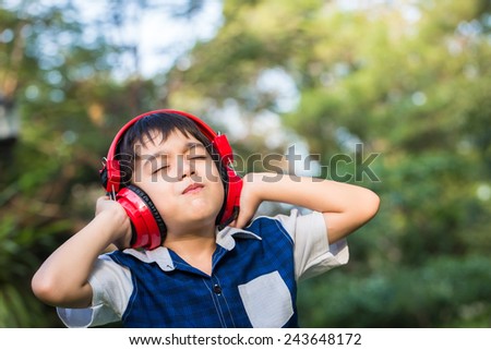 Little boy listening the music with headset in park