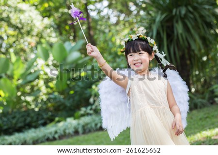 Little cute girl in angel dress with smiling face in the park