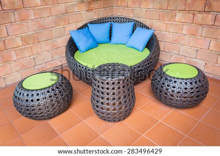 sofa furniture weave Rattan stick chair with blue pillows on orange tile and old brick wall