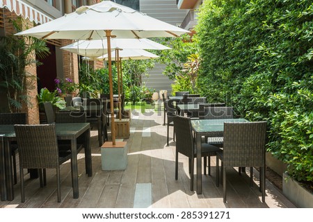 Cafe tables and chairs outside with big white umbrella and plant