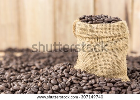 coffee beans in bag on roasted coffee seed and wooden background