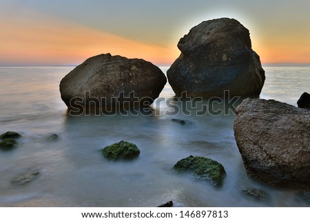 Stone on seashore in evening time after sunset
