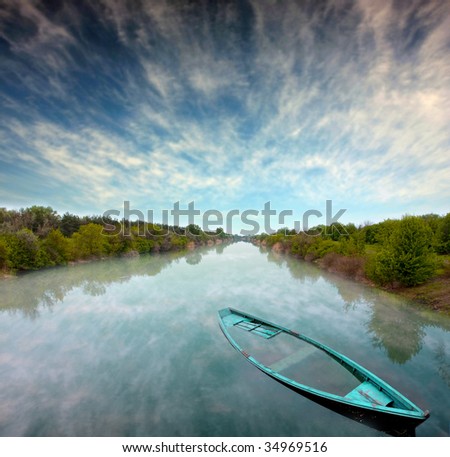 Mystical landscape with flooded boat in river and clouds