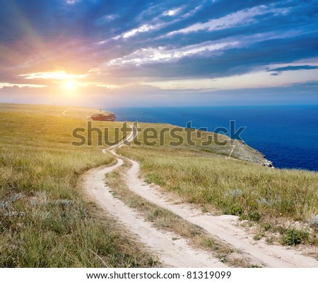 Countryside road near sea on sunset sky background