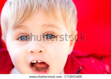 Portrait of a little boy with blue eyes yelling joyfully with delight