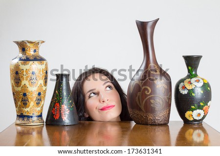 Girl head with vases on table admiring one of the vases