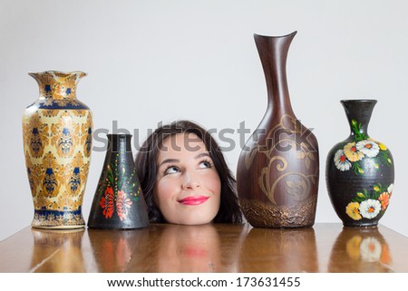Girl head with vases on table smiling at one of the vases