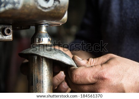 Man hands closeup working with a metal pressing machine