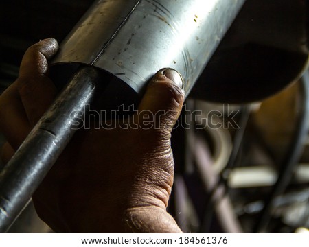 Man\'s hand holding a metal cylinder at work