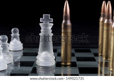 Machine gun bullets on glass chess board on black background