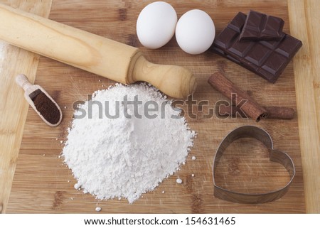 Baking ingredients and tools on brown wood cutting board
