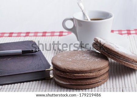 Big round brown  cookies with  old notebook and fountain pen with coffee mug in the background