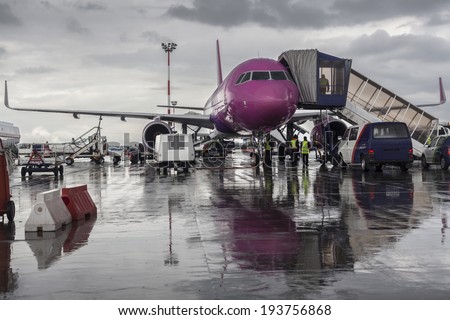 Purple airplane on the ground with maintenance cars around