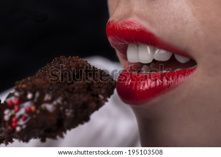 Young girl mouth with red lips eating chocolate cake