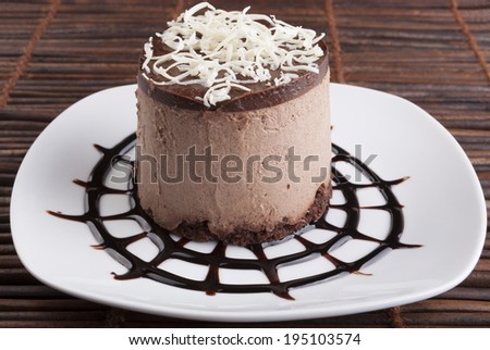 Brown Chocolate mousse cake with white chocolate on top placed on chocolate spider web shape