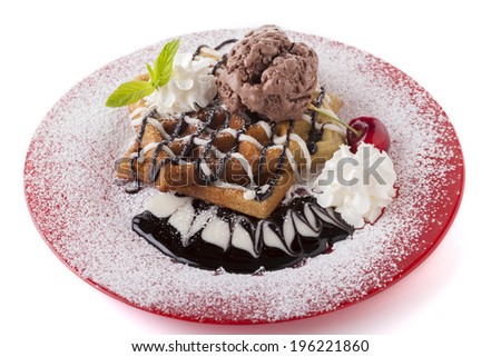 Belgian waffle with chocolate syrup whipped cream and red cherry on red plate